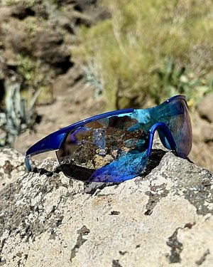 Bild einer verspiegelten Sport-Sonnenbrille, die draußen auf einem Stein liegt.